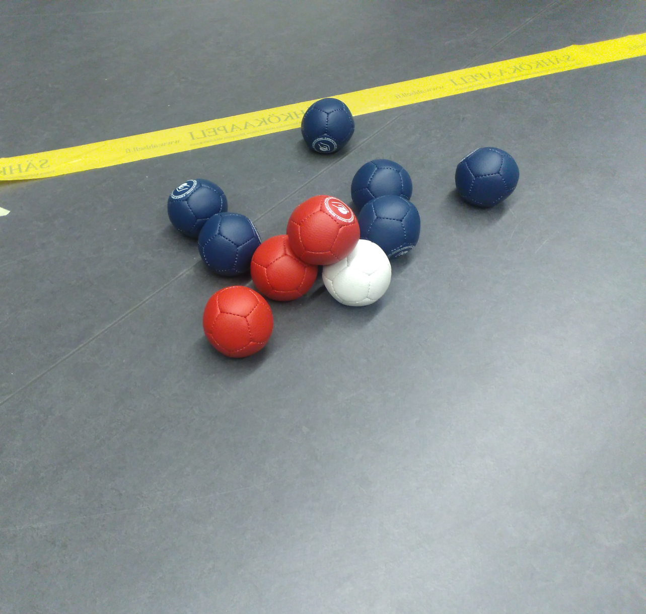 punaisia ja sinisiä boccia-palloja valkoisen ympärillä
