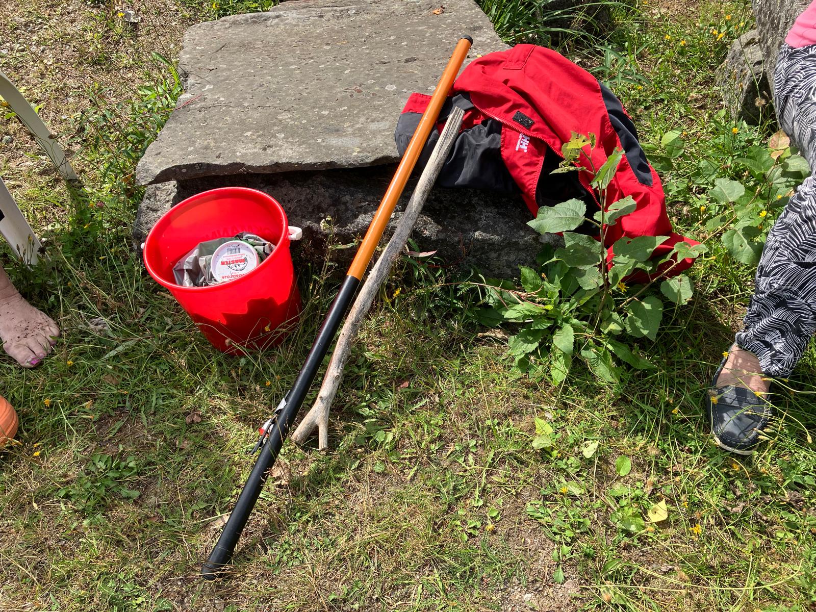 Punainen ämpäri, jossa kaloja. Vieressä onki ja tainnutuskeppi.