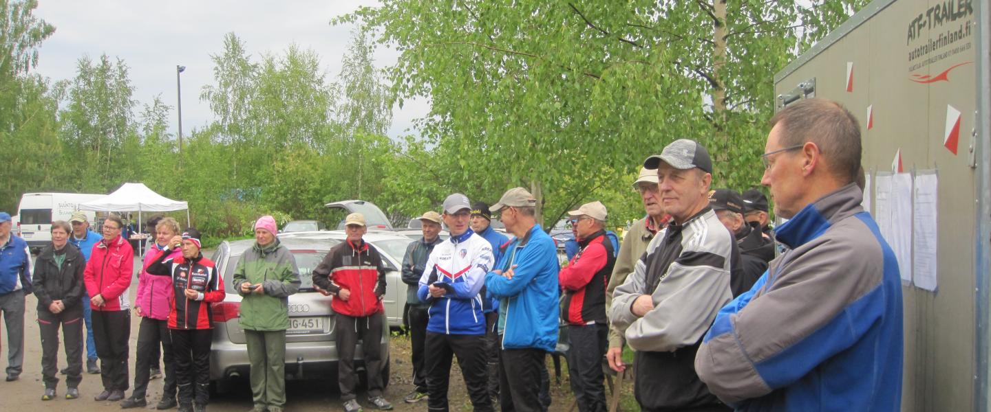 Suunnistajien joukko odottamassa palkintojen jakoa sateisessa säässä Kauhavalla 3.6.2019