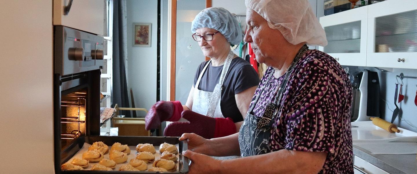 Emäntätoimikunnan jäsenet leipomassa pullaa.