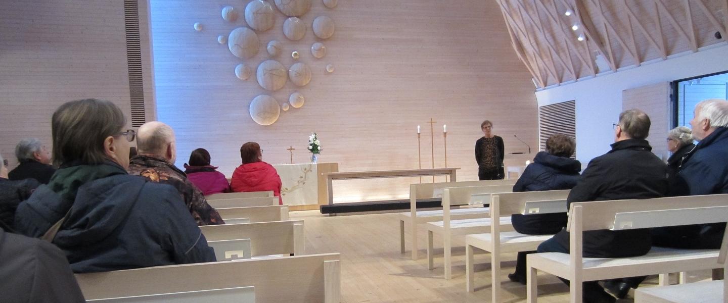 Kuokkalan kirkossa Jyväskylässä vieraat ihastelevat kaunista alttaritaulua