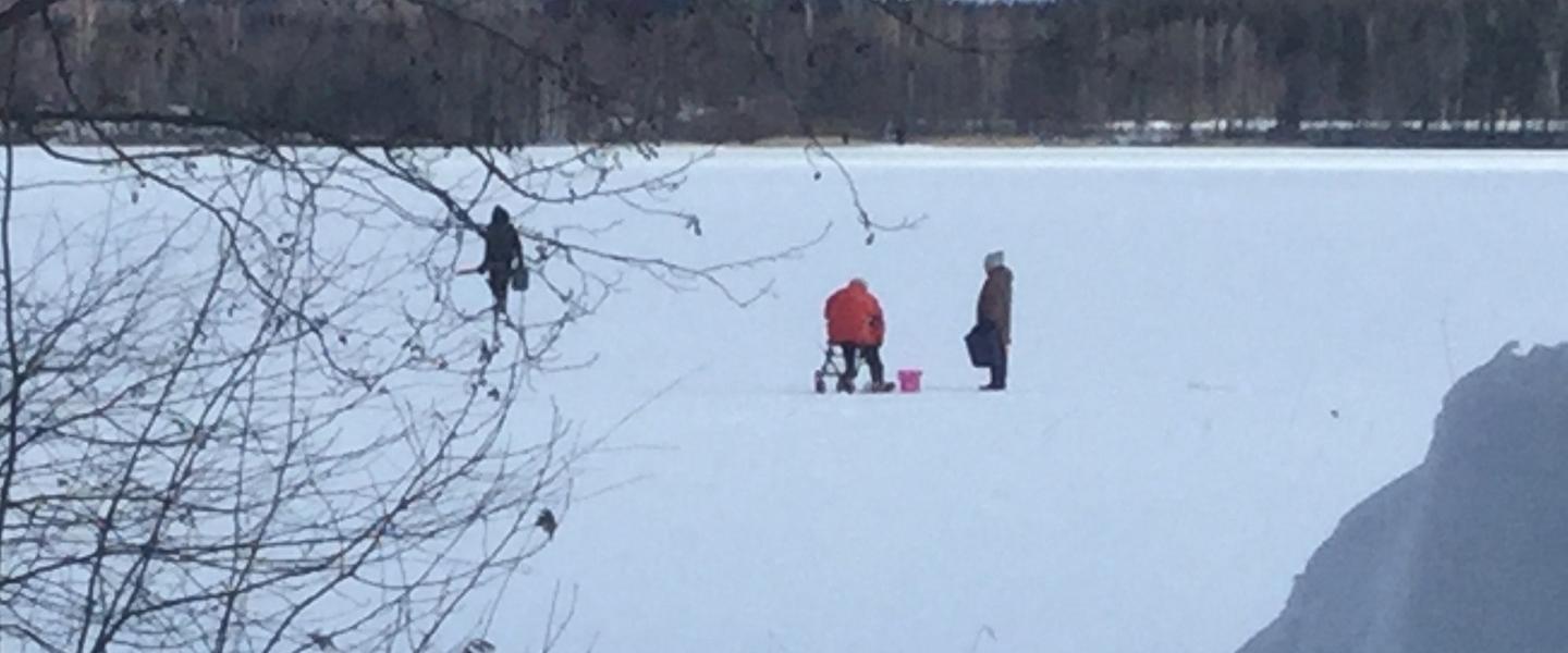 Luminen maisema, jossa kolme henkilöä ovat pilkkimässä