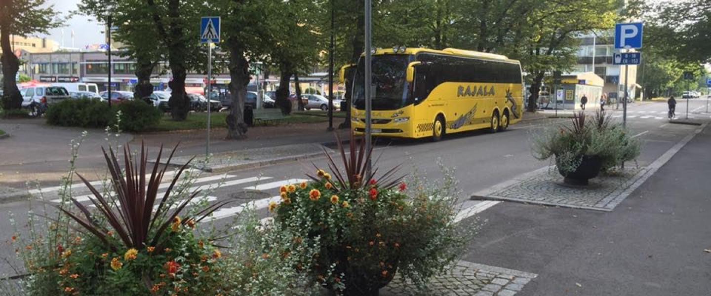 Kuva jostain kaupungista, jossa keltainen bussi kuvan keskellä