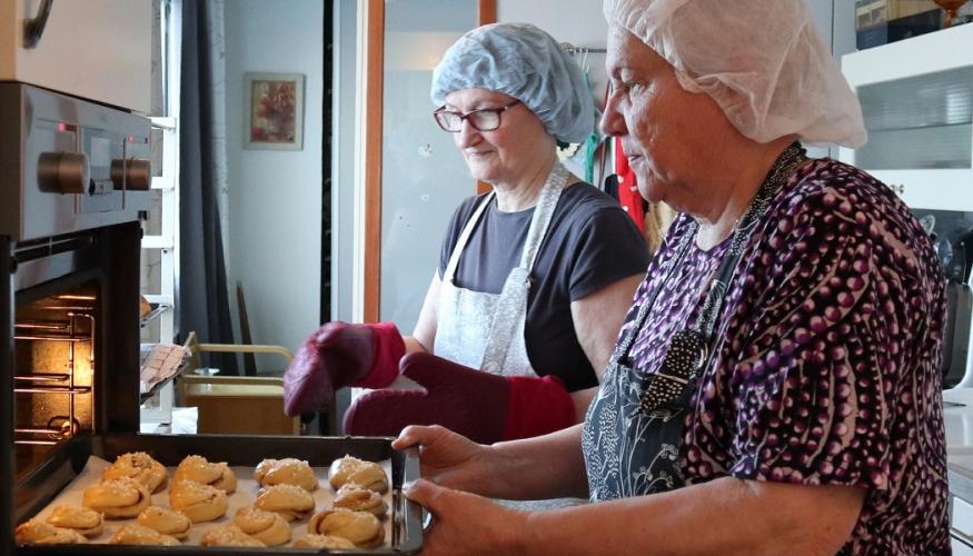 Emäntätoimikunnan jäsenet leipomassa pullaa.
